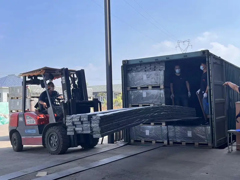 Forklift loading composite decking into a shipping container at factory yard