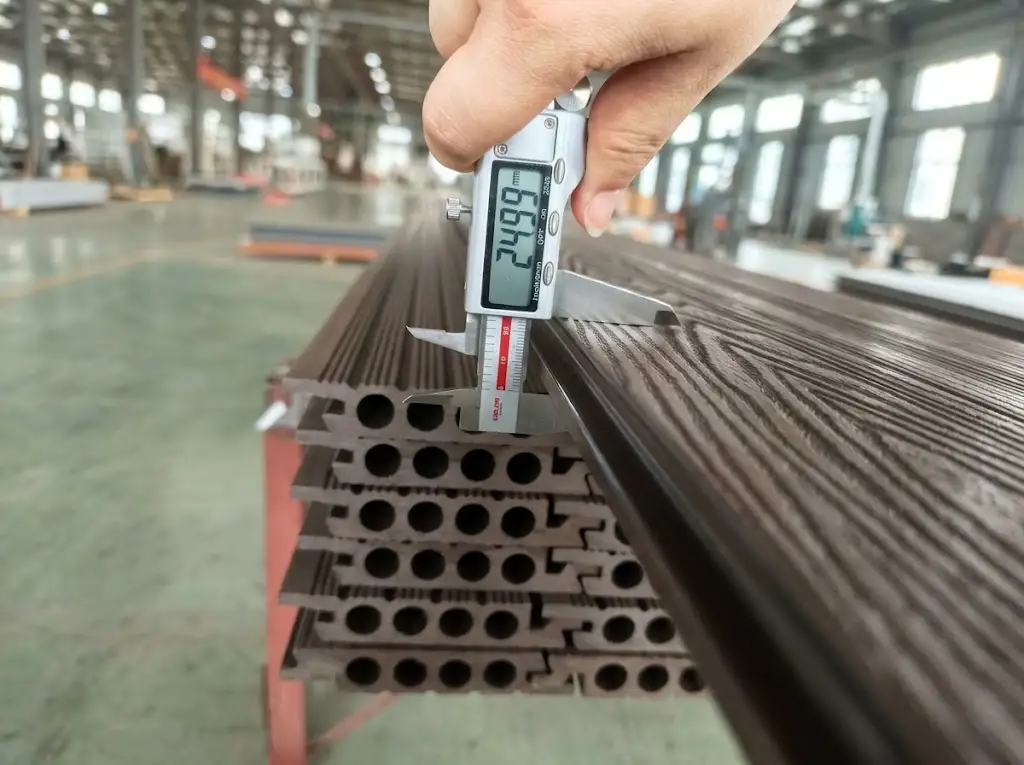 Quality inspector measuring profile thickness for hollow wpc decking using a digital caliper.