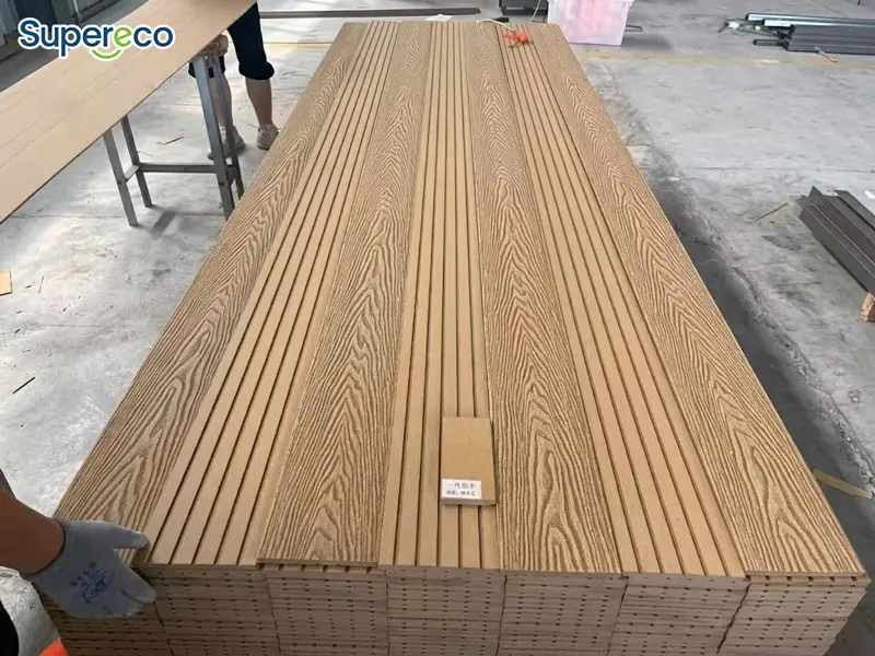 Teak-colorsolid WPC decking boards with grooved surfaces arranged in a factory