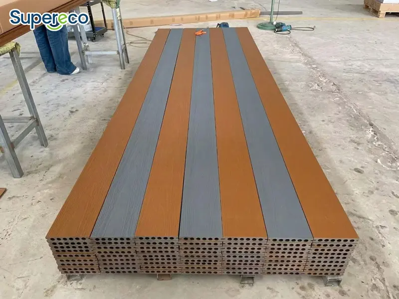Orange and gray WPC decking boards arranged side by side with round hollow profiles